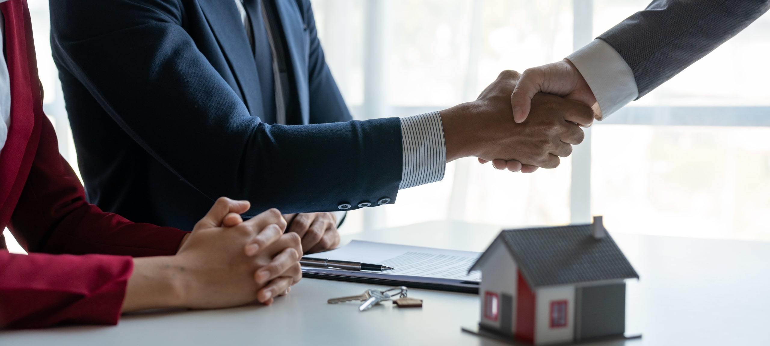 Realtors shaking hands with client over completed deal